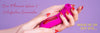 A close-up of hands with red manicured nails holding a bright pink personal massager against a lavender background, with promotional text reading 'Our Pleasure Wave 3 Satisfaction Guarantee' and 'WAVE HI OR SAY BYE.
