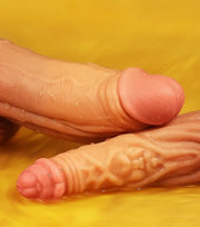Two realistic flesh-toned dildo toys with pinkish bases, photographed close-up on a bright yellow background.